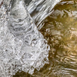 Close-up of icicles on rock by lake