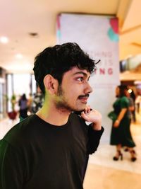 Man looking away while standing in shopping mall