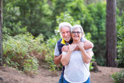 Portrait of smiling senior couple standing against trees