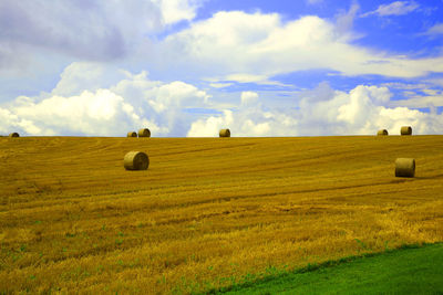 Hay bales on field against sky