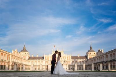 Woman standing in front of buildings against cloudy sky
