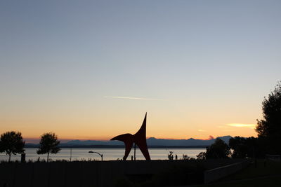 Silhouette people by sea against clear sky during sunset