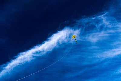 Low angle view of people paragliding against blue sky