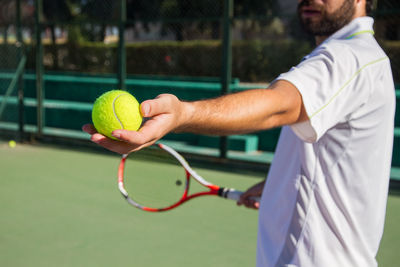 Midsection of man playing tennis at court