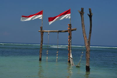 View of wooden post and flag against sea