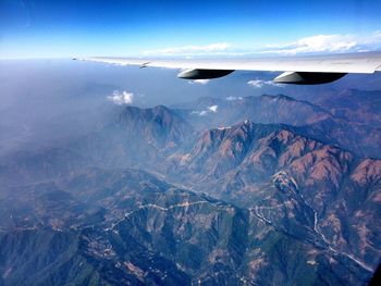 Cropped image of airplane wing over rocky mountains