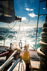 Block and tackle on a wooden sailing yacht, the sun reflecting off the ocean.