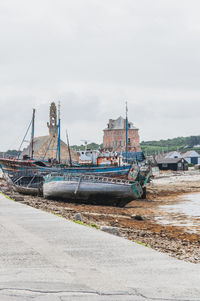 Abandoned boats moored on beach against sky