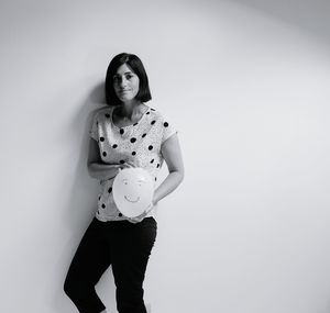 Portrait of young woman standing against white background