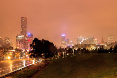 Illuminated buildings in city against sky at night