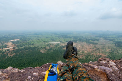 Rear view of man sitting on landscape against sky