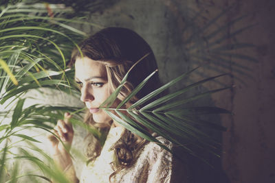 Woman with plant against wall