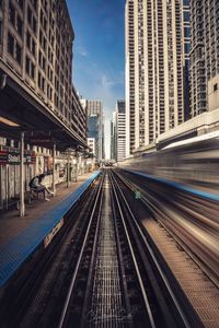 Railroad tracks amidst buildings in city against sky