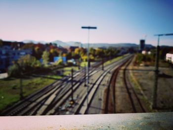 Railroad tracks by street against clear sky