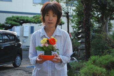 Portrait of woman standing by flowering plants