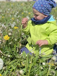 Boy holding plants on field