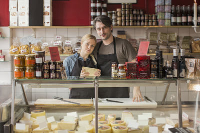 Portrait of male and female worker standing at display cabinet in supermarket