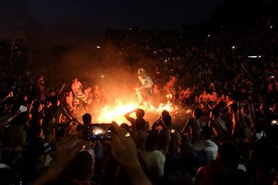 Man with fire performing amidst crowd at night