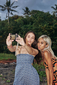 Two bestfriends girls sweet loving taking picture at the beach moodyon film retro dresses fun