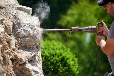 Side view of man holding equipment on rock