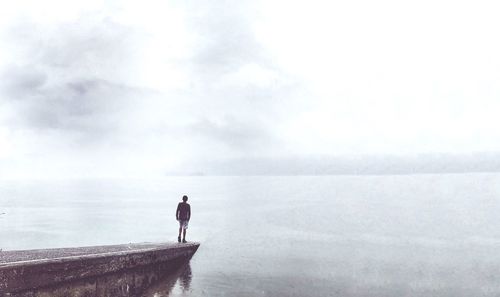 Rear view of man walking on sea against sky