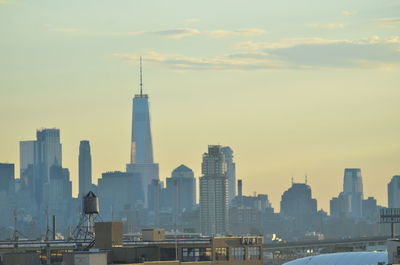 Modern buildings in city against sky during sunset