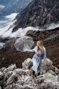 Woman standing on rock with umbrella 