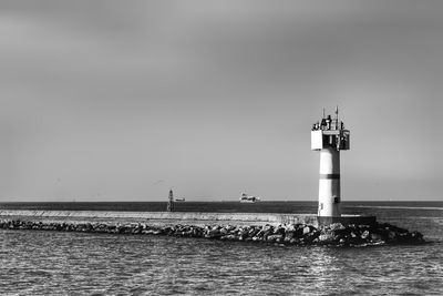 Lighthouse by sea against sky