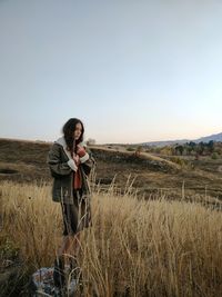 Young woman standing on field against clear sky