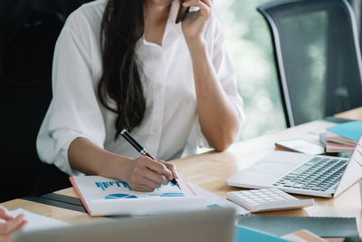 Midsection of business colleagues working at desk in office