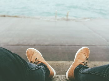 Low section of man wearing shoes sitting on promenade