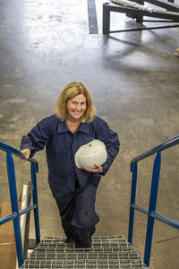 Portrait of smiling woman standing against railing