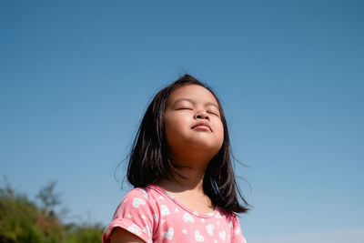 Portrait of a girl against clear blue sky