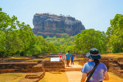 Rear view of people walking on rock against trees