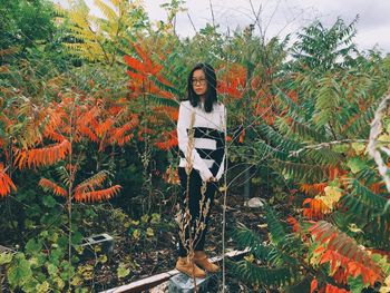 Portrait of smiling young woman against trees