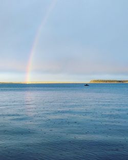 Scenic view of rainbow over sea against sky