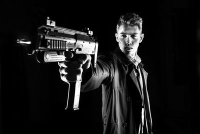 Portrait of man holding camera against black background