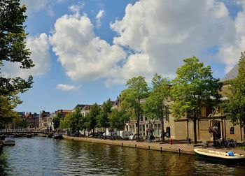 People by river against sky in city