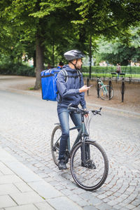 Full length of food delivery man on bicycle at street