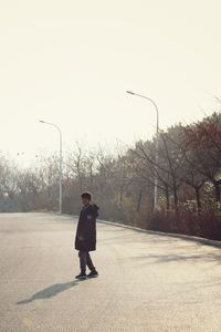 Full length of man standing on road against clear sky