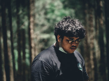 Portrait of young man looking away in forest