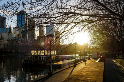 Buildings by river in city against sky