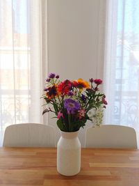 Flower vase on table against window at home. centerpiece 