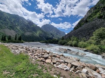 Scenic view of river by mountains against sky