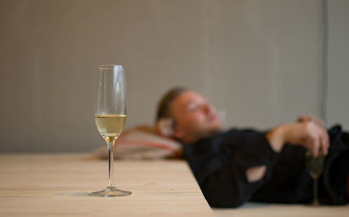 Champagne flute on table with man sleeping at home