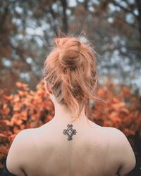 Rear view of woman standing against trees in forest