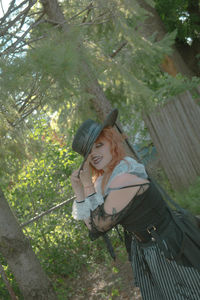 Portrait of young woman sitting on tree