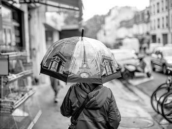 Rear view of man with umbrella on street during rainy season