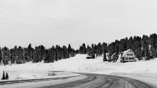 Road by snow covered trees against sky