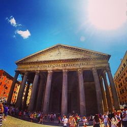 Low angle view of tourists against blue sky